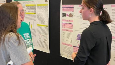 Student showing research poster to others